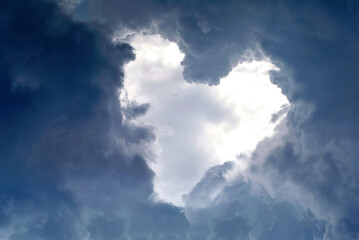 Fototapeta na wymiar Heart shape appears in the cloudy dramatic sky. Heart frame shaped clouds on sky background..