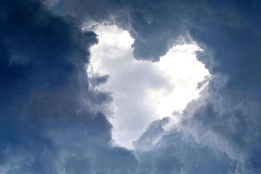 Heart shape appears in the cloudy dramatic sky. Heart frame shaped clouds on sky background..