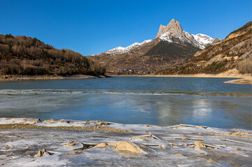 Lanuza reservoir (Huesca), frozen water and first snow in the mountains.