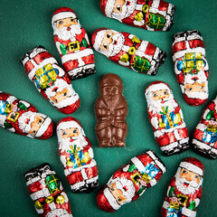 Chocolate Santa candies on a green chalkboard background. Sweets and holidays