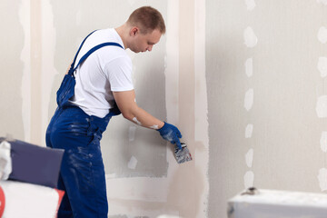 Man plastering wall with putty knife indoors. Home renovation