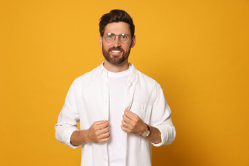 Portrait of smiling bearded man with glasses on orange background