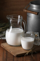 Tasty fresh milk in can, jug and glass on wooden table