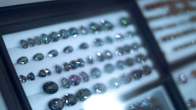 Collection of beautiful expensive gems behind the glass of a jewelry store showcase shine brightly with their faces. Shot in motion. Closeup. Macro. Shallow depth of field