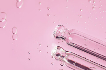Pipettes near serum drops on beautiful mirror, closeup with space for text. Toned in pink