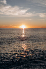 Calm sea with sunset sky and sun through the clouds over. Meditation sea and sky background.