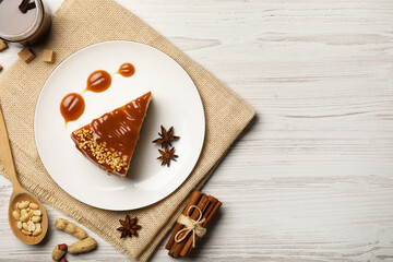 Tasty cheesecake with caramel and nuts served on white wooden table, flat lay. Space for text