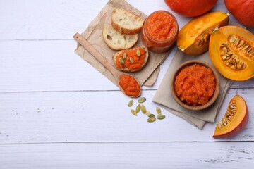 Delicious pumpkin jam and fresh pumpkin on white wooden table, flat lay. Space for text