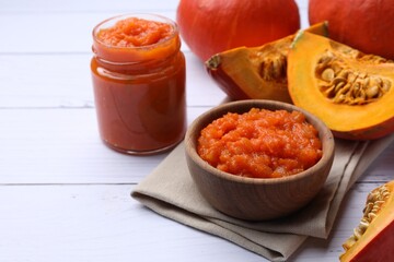 Delicious pumpkin jam and fresh pumpkins on white wooden table