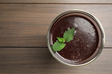 Glass of delicious hot chocolate and fresh mint on wooden table, top view. Space for text