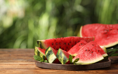 Slices of delicious ripe watermelon on wooden table outdoors, space for text