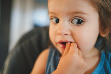 Close-up portrait of a girl looking focused to one side holding her hands in her mouth. Healthy nutrition for kids. Children , the safety of children.
