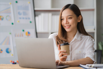 Young asian businesswoman beautiful charming smiling and using on mobile phone in the office