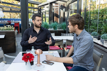 Two male friends talking in the cafe bar