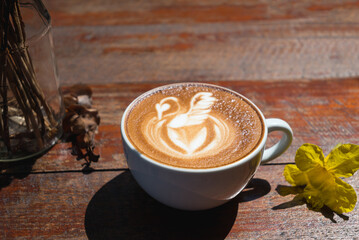 Latte art coffee with swan shape in coffee cup on wooden table, Hot drink