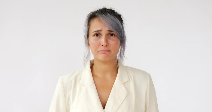 Pretty woman looks directly, straight to camera, with empathy, nearly crying at what she sees or hears. Portrait shot of young Caucasian lady with colored hair against white background