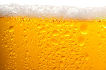 Glass of tasty cold beer with foam and condensation drops on white background, closeup