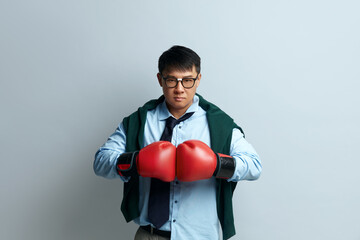 Angry Guy Boxing Studio. Portrait of Asian Man Standing with Boxing Fists and Ready to Attack or Defence, Looking with Angry Face, Aggression. Indoor Studio Shot Isolated on Grey Background 