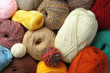 Different balls of woolen knitting yarns as background, top view