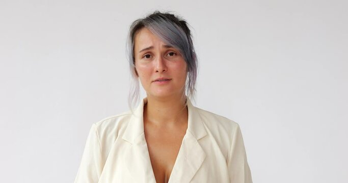 Pretty woman relives memories or hears something bad, suffers and is tormented, almost crying. Headshot footage of young Caucasian lady with dyed hair on white background