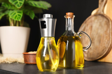 Bottles with cooking oil and bowl of sunflower seeds on black table in kitchen