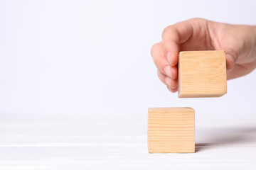 Woman arranging cubes on white background, closeup with space for text. Idea concept