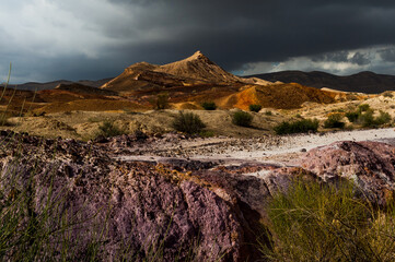 Dark clouds hover over a mountain peak and purple rocks of the mineral-rich Colored Sands Nature Reserve in the Negev Desert in southern Israel.