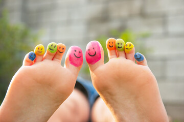 Teenage girl with smiling faces drawn on toes outdoors, closeup