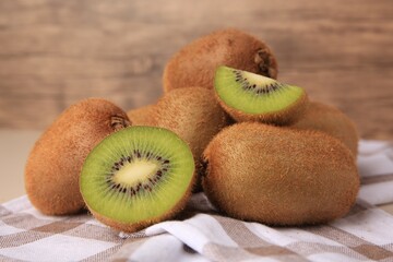 Heap of whole and cut fresh kiwis on checkered tablecloth, closeup
