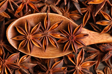 Aromatic anise stars and wooden spoon on table, closeup