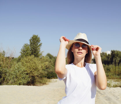 Portrait of an american woman with dark glasses and a hat in the desert near the forest. Brown tint. woman looking