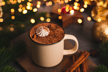 A mug of hot chocolate with cinnamon and spices on the Christmas table. Hot winter drink