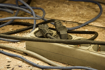 Messy outlet power extension cord on an apartment floor with plugs plugged in. Cable power cords in...