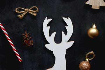 Small presents, various Christmas ornaments and deer figurine on dark background. Top view.
