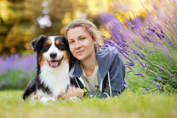 Blonde woman laying at the lawn with her australian shepherd