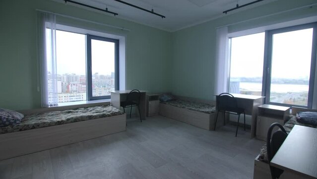 Comfortable beds with tables and cabinets for tenants in student dormitory room. Housing service in modern hostel