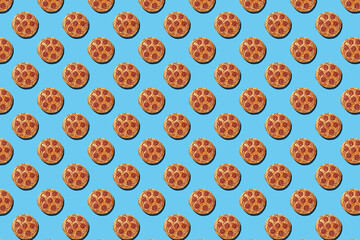 A hard light pattern of whole salami pizza pieces on a seamless bright blue background, top view