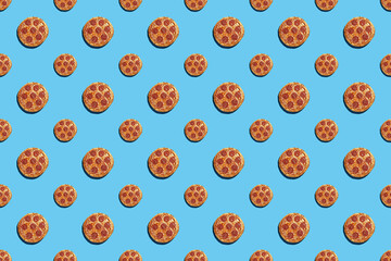 A hard light pattern of whole big and small salami pizza pieces on a seamless bright blue background, top view