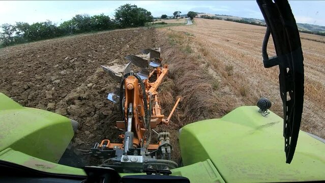 Pov tractor with furrow plow tool working the ground for agriculture