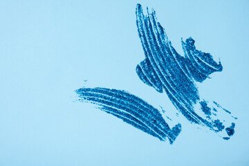 Blue glitter smear on colored background top view. Christmas glitter element