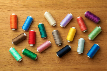 Many colorful sewing threads on wooden table, flat lay