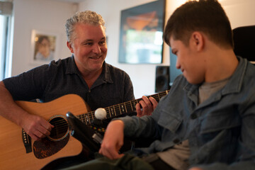 Father playing guitar with disabled son