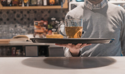 Camarero irreconocible, sirviendo té con bandeja, en la barra de una cafetería. - obrazy, fototapety, plakaty