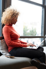 Woman working on laptop by window
