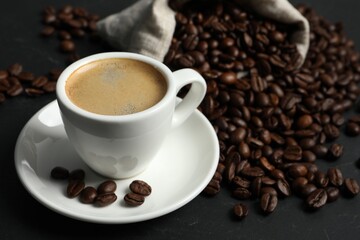 Cup of aromatic coffee and beans on grey table. Space for text