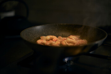 The cook cooks shrimp in the pot. The black pot heats up over the kitchen fire and cooks fresh, tasty shrimp.
