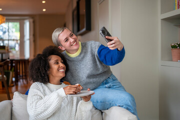 Smiling lesbian couple taking selfie at home