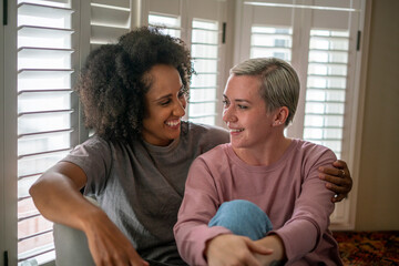 Smiling lesbian couple embracing at home