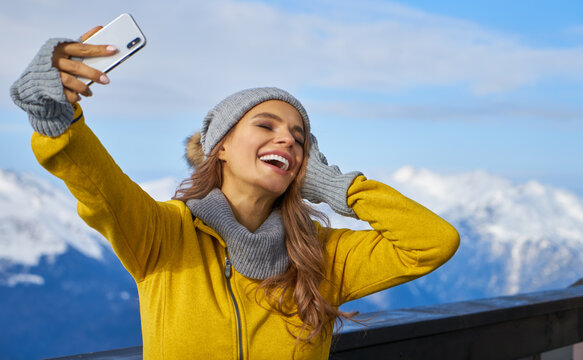 technology and leisure concept - happy woman in winter fur hat taking selfie by smartphone outdoors