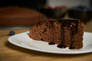 Handmade chocolate cake decorated with cranberries and red currants on the wooden kitchen table.